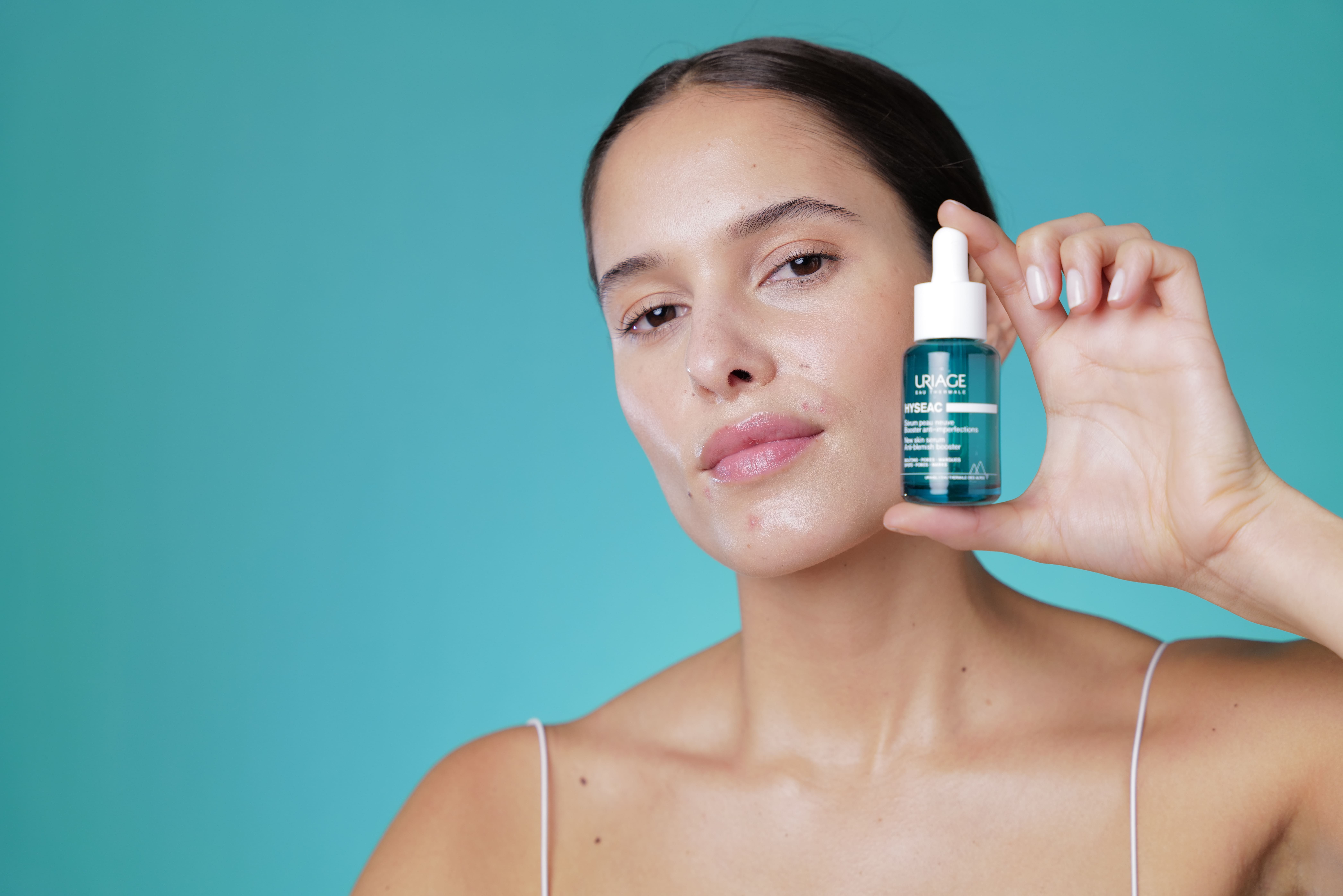 Modella che applica il siero Uriage Hyseac Pelle Nuova sul viso.