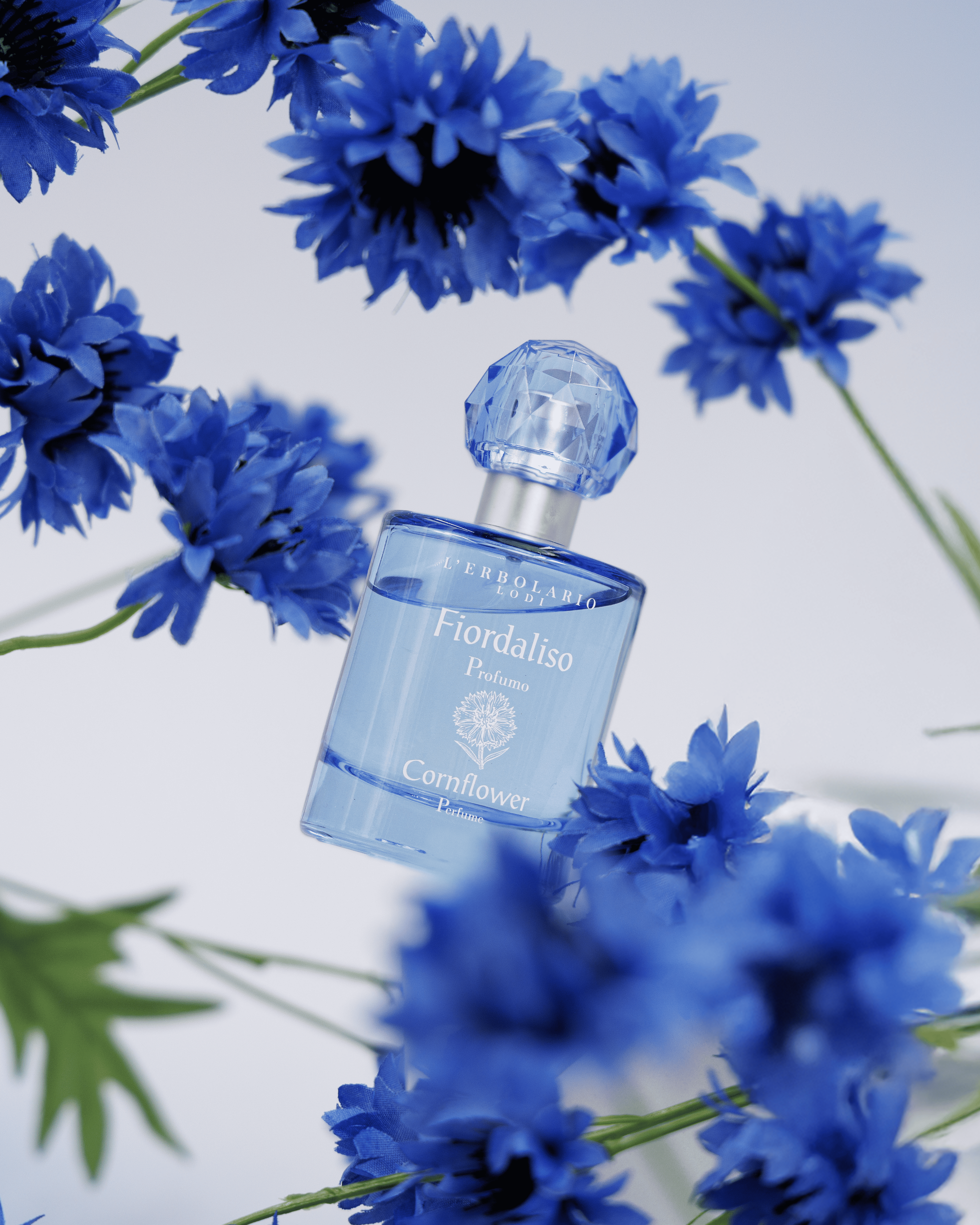 Bottiglia di profumo Fiordaliso di Erbolario con fiori di Fiordaliso sullo sfondo