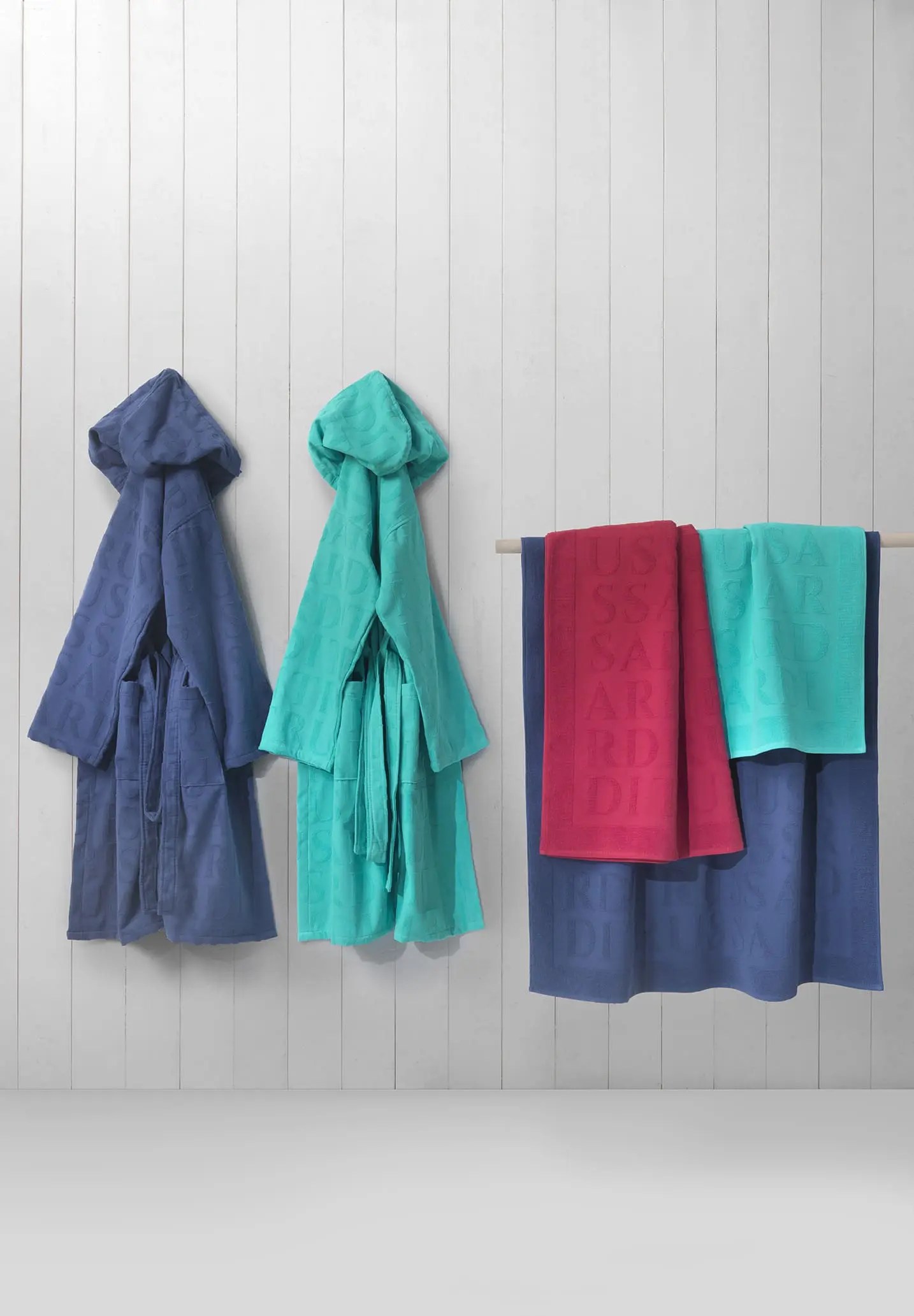 Teli mare e accappatoi eleganti firmati Mirabello Carrara e Trussardi Casa, realizzati in morbido cotone e velour, per un’estate raffinata e confortevole.