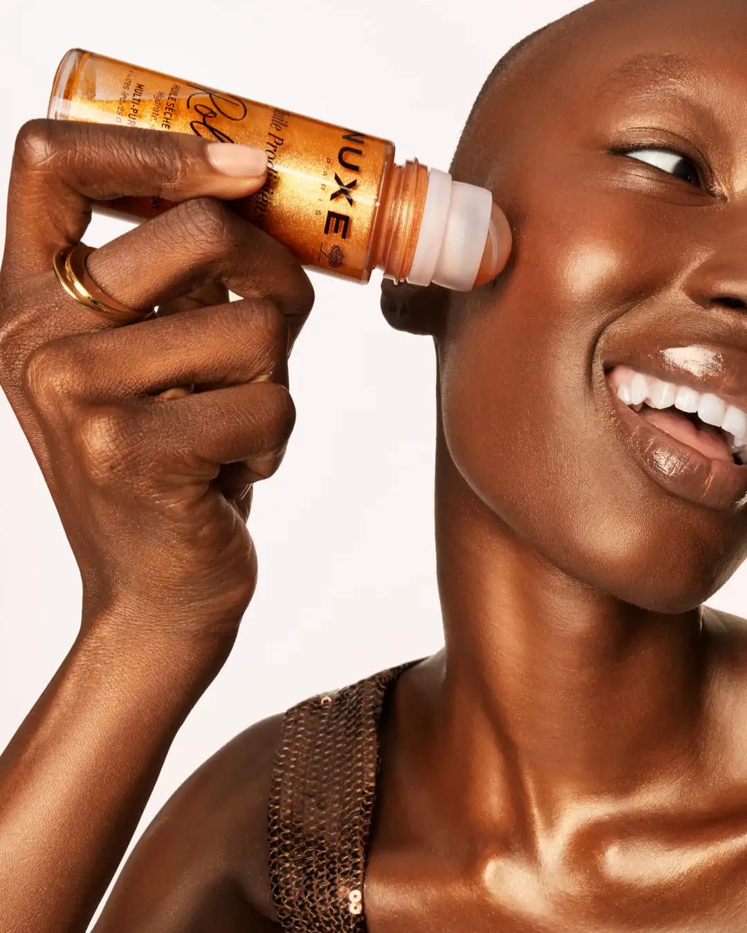 Dettaglio della texture luminosa e dorata di Huile Prodigieuse® Or Roll-On applicata sulla pelle radiosa di una modella