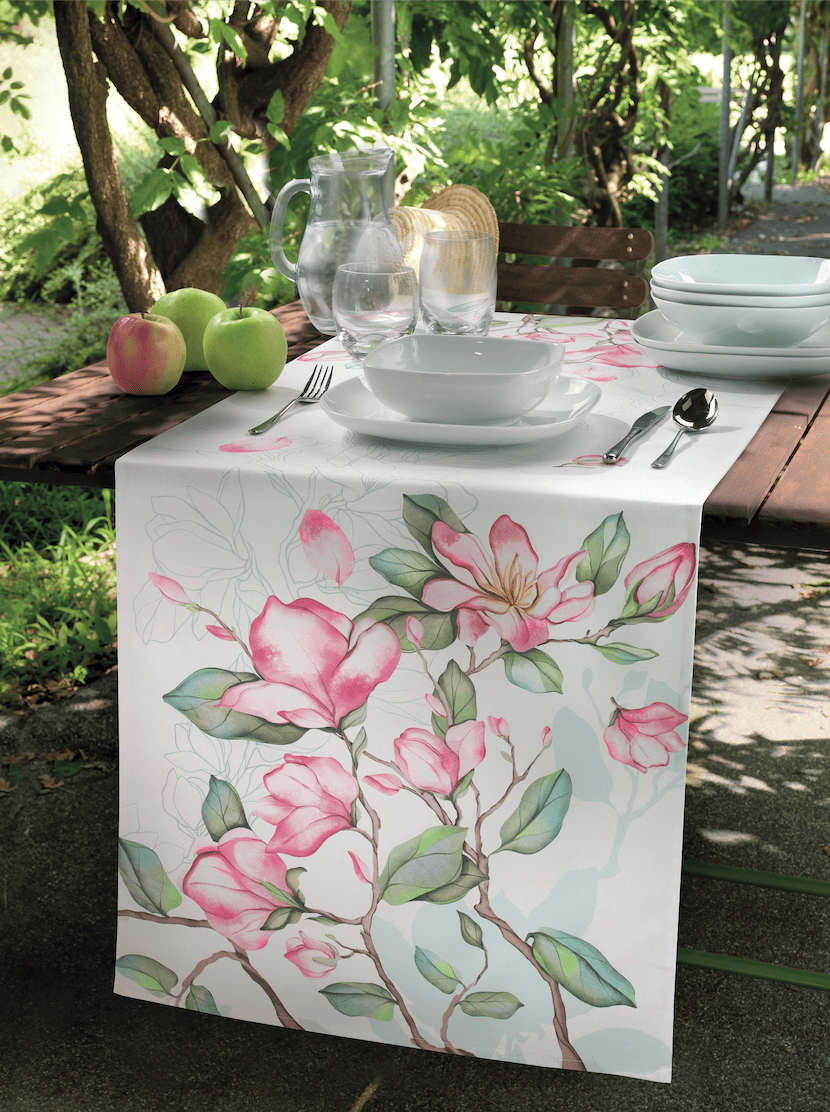 Tavola all’aperto con tovaglia a fiori e mise en place colorata