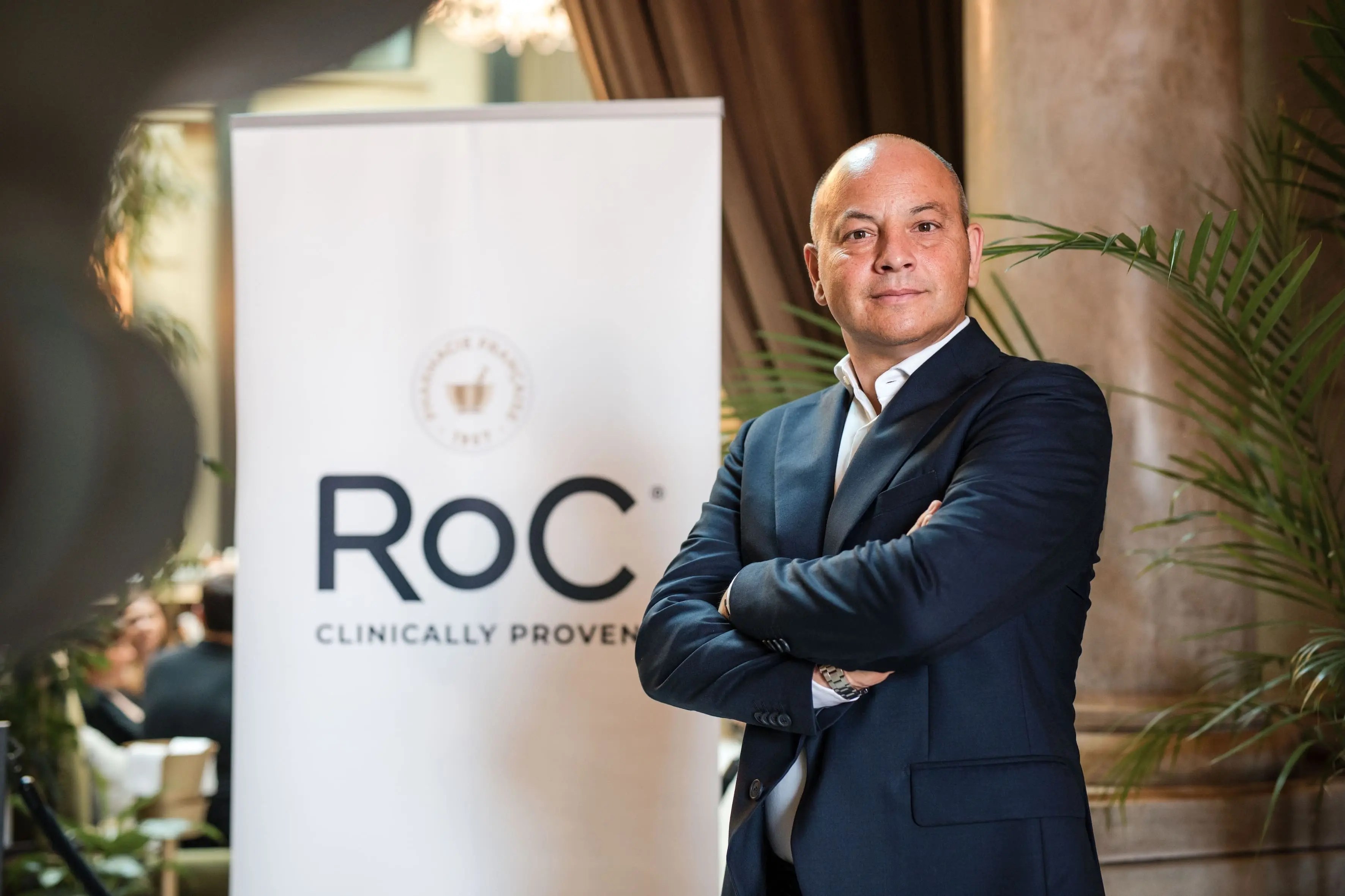 Logo RoC® Skincare con skyline di Milano sullo sfondo, simbolo del rilancio globale del brand