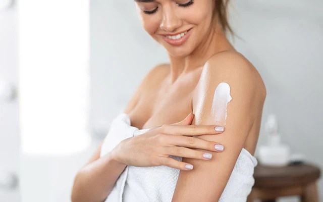 Donna che applica crema corpo, guida completa ai trattamenti anticellulite per pelle liscia e tonica